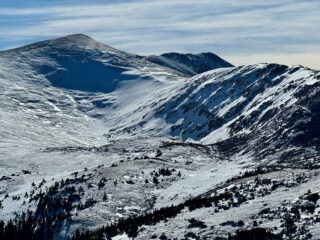 Dec 30, 2025: La Cal Basin, strong winds with this last storm have stripped windward slopes and deposited snow on the leeward sides of others. Slopes like these above treeline, is where you could find a cohesive slab that rests on top of weak faceted snow beneath